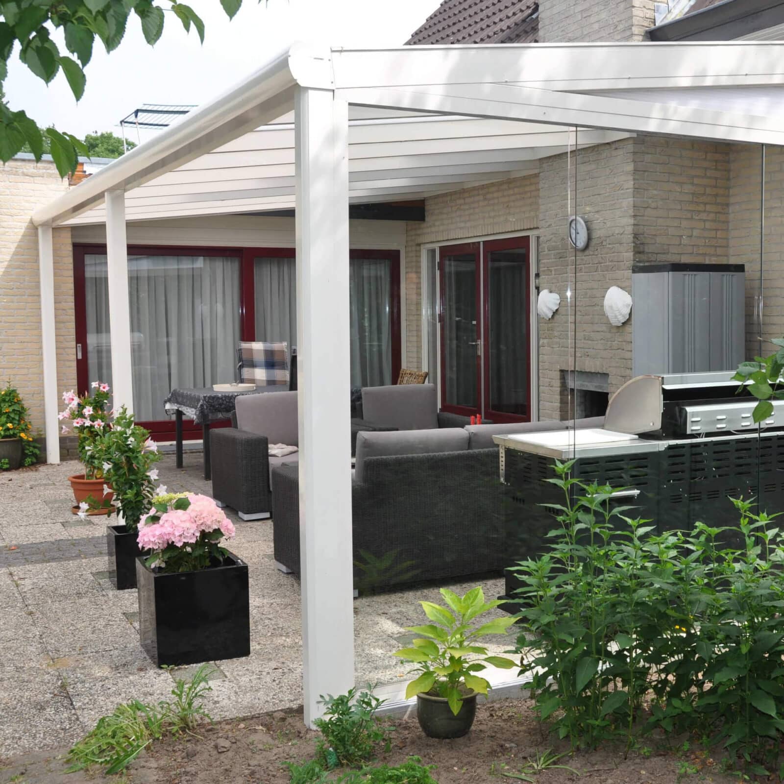 Witte terrasoverkapping met daaronder een zithoek.