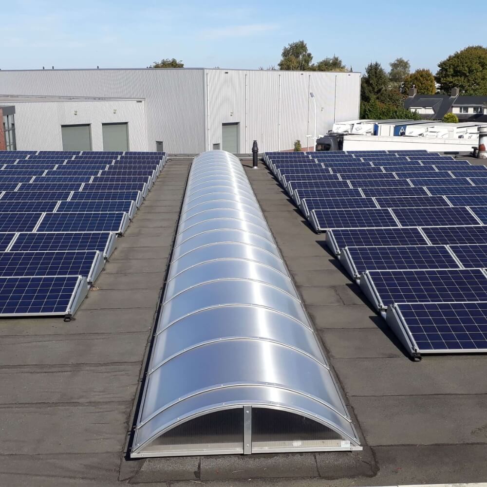 Gebogen lichtstraten - elegantie en efficiëntie Moderne gebogen lichtstraten op een industrieel dak, harmonieus geïntegreerd tussen zonnepanelen