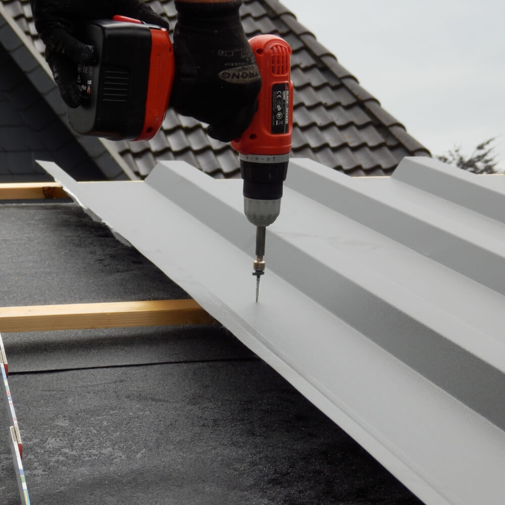 Professionele installatie van een dakplaat met accuschroevendraaier, veilig dakwerk met gereedschap en handschoenen